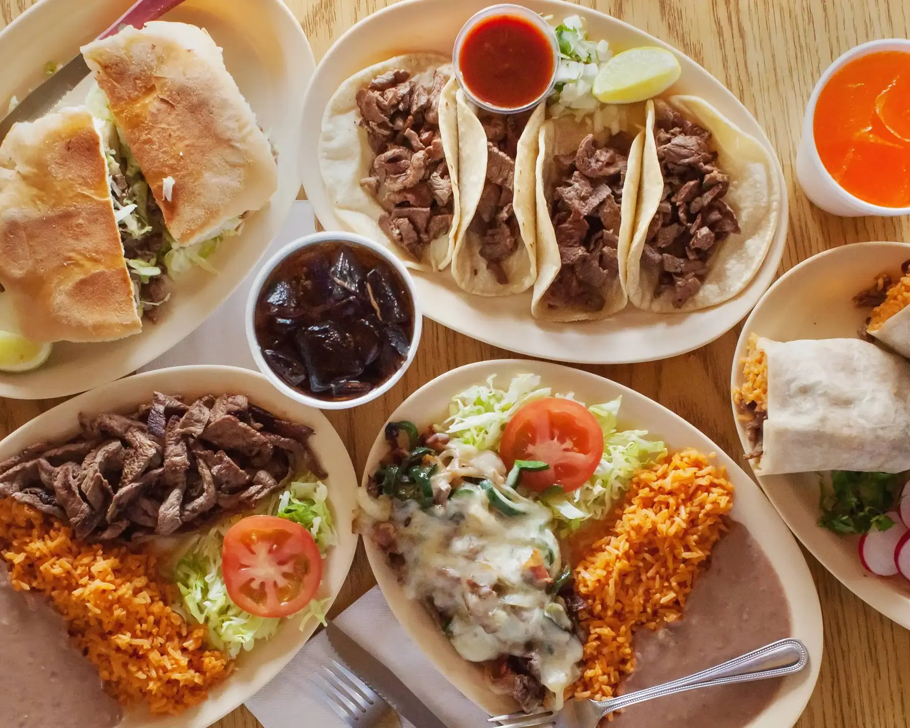 La Patrona table spread with tacos, plates, rice, beans, salsa, and tortas